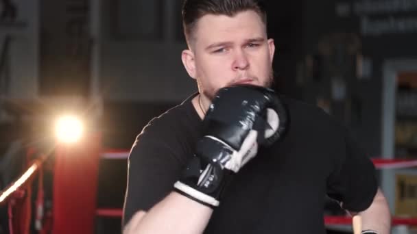 Een mannelijke bokser trekt bokshandschoenen aan in de sportschool — Stockvideo