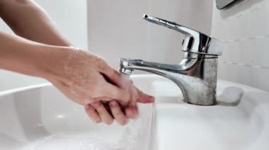 Mikropları yok etmek ve tuvaleti kullandıktan sonra enfeksiyonun yayılmasını önlemek için el yıkama kavramı. Banyo lavabosunda el yıkamanın yakın görüntüsü..
