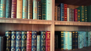 Koyu dikenli dikenler üzerinde altın desenli, ahşap raflara dizilmiş birkaç kitabın yatay ağır çekimleri.