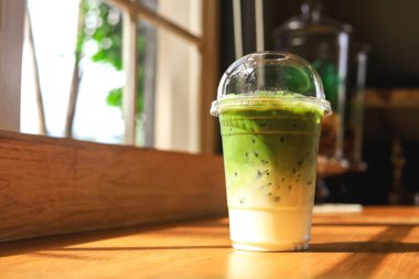 Buzlu yeşil çay, kahve dükkanında, plastik bardakta süt, ahşap masada..