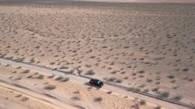 Las Vegas yakınlarındaki Mojave Çölü 'nde tek başına seyahat eden 4 tekerli siyah bir aracın görüntülerini izliyoruz.