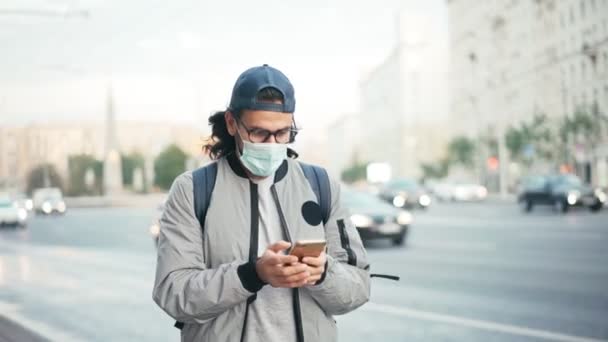 Jeune homme dans un masque protecteur debout dans la rue contre la route — Video