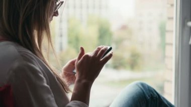 Cep telefonu kullanan genç bir kadının yakın plan fotoğrafı..