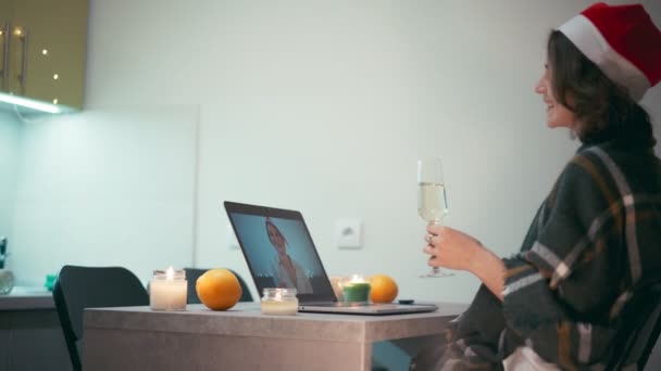 Uma jovem mulher bebendo champanhe enquanto conversa com um amigo através de uma chamada de vídeo — Vídeo de Stock
