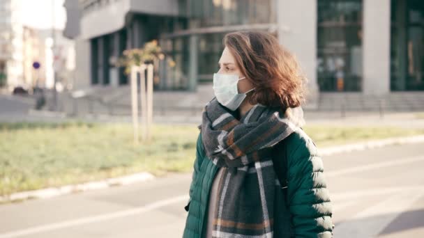 Молодая женщина в медицинской защитной маске стоит на улице. — стоковое видео