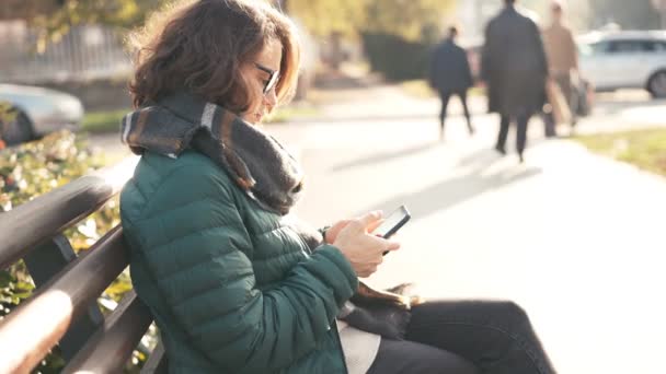 Close-up shot van een jonge vrouw in bril scrollen nieuws in haar smartphone — Stockvideo