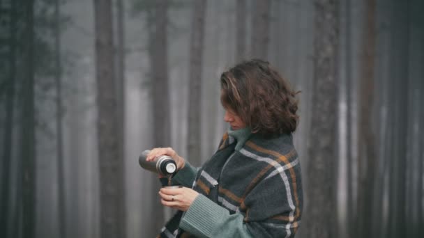 Geniş, rahat bir eşarba sarılmış genç bir kadın termostan çay içiyor. — Stok video