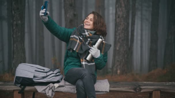 Młoda wesoła kobieta robi selfie na swoim smartfonie w mglistym jesiennym lesie — Wideo stockowe