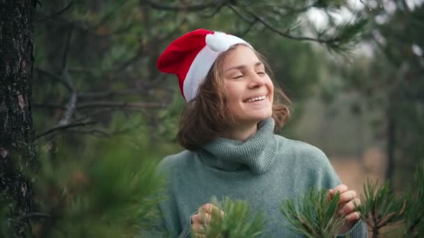 Uma jovem mulher alegre em um chapéu vermelho Santas apreciando a vista de uma floresta — Vídeo de Stock