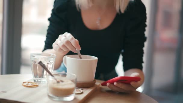 Bir kadının fincanda kremayla kahve karıştırdığı yakın plan bir fotoğraf. — Stok video