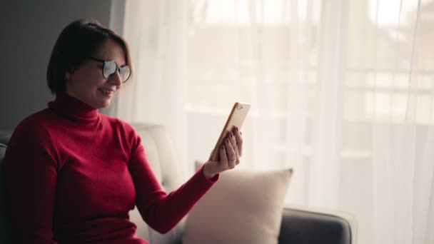 A cheerful young woman in glasses taking a video call with her smartphone. — Stock Video