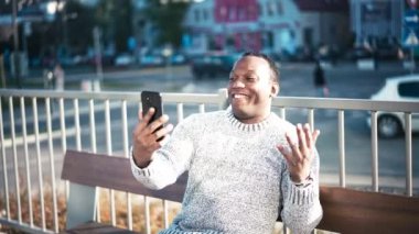 Genç, Afro-Amerikalı Amerikalı adam akıllı telefonuyla video görüşmesiyle konuşuyor.