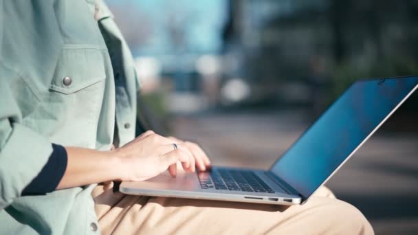 Primer plano de las manos de la mujer escribiendo en un ordenador portátil al aire libre en un día soleado. — Vídeos de Stock