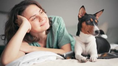 Genç bir kadın köpeğiyle yatakta yatarken rahatlıyor ve rüya görüyor.