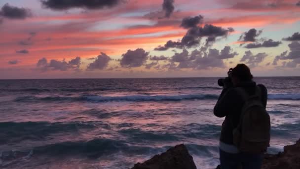 Фотограф фотографує великі хвилі, що падають на каміння — стокове відео
