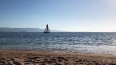 Güneşli bir günde denizde yelken açan bir yat manzarası..