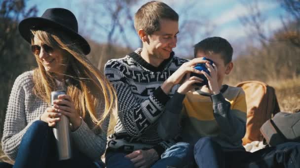 Счастливая семья хорошо проводит время, выпивая чай из термоса на открытом воздухе — стоковое видео