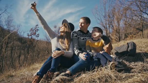 Una giovane famiglia felice si fa un selfie con uno smartphone all'aperto in una giornata di sole — Video Stock