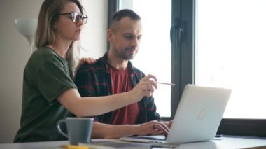 Odaklanmış genç çift karı koca içeride dizüstü bilgisayara bakıyor.