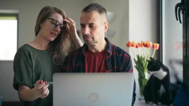 Happy young adult couple using a laptop doing online shopping together. — Stock Video