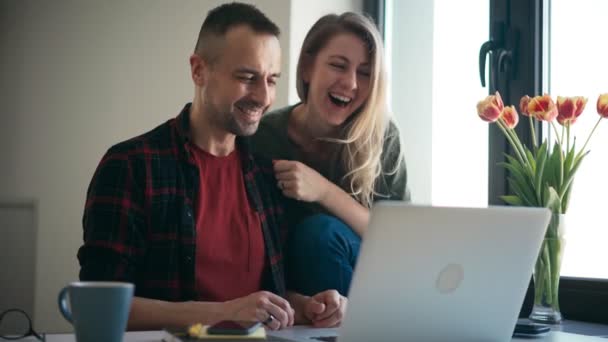Sebuah pasangan yang ceria membuat panggilan video dengan teman-teman atau keluarga di laptop — Stok Video