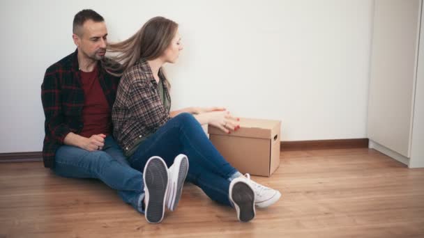 An adult couple having fun while unpacking the cardboard box after moving — Stock Video