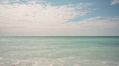 Güneşli bir günde deniz dalgaları ve bulutların sakin minimalist görüntüsü.