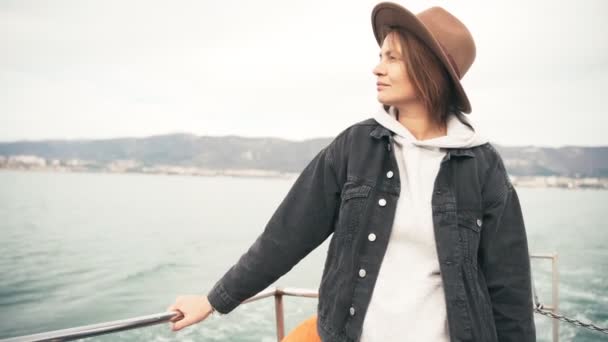 Una bella giovane donna in giacca e cappello gode di una gita in barca di mare — Video Stock