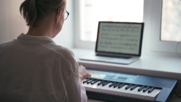 Rückenaufnahme einer jungen Frau, die auf einer Klaviertastatur spielt — Stockvideo