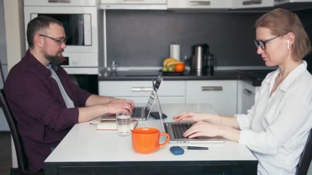 Una joven pareja hombre mujer freelancers empleados remotos trabajando desde casa — Vídeo de stock