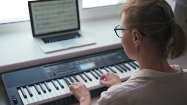 Hátulról egy fiatal nő játszik egy zongora billentyűzeten — Stock videók