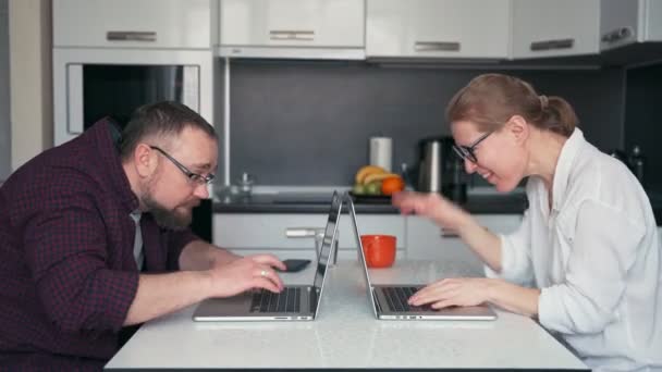 Una joven pareja de hombres y mujeres locos escribiendo en sus computadoras portátiles. — Vídeos de Stock