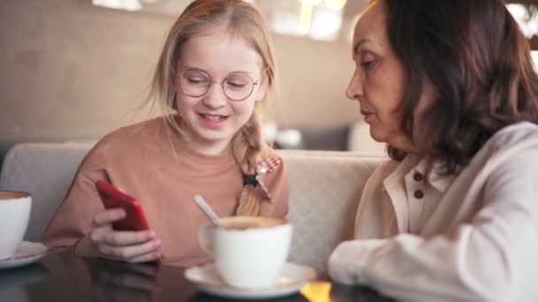 Feliz abuela y linda nieta usando el teléfono móvil juntos — Vídeos de Stock