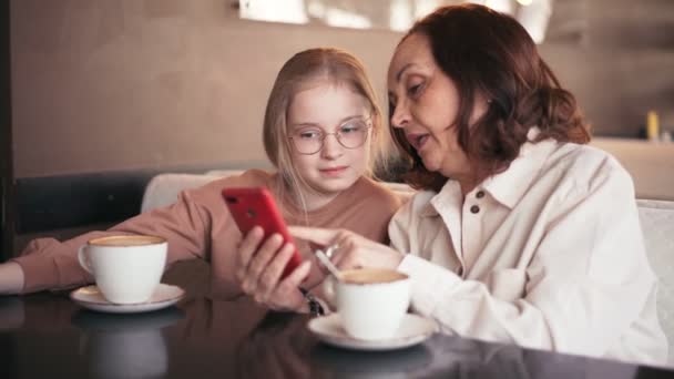 Счастливая бабушка и милая внучка вместе пользуются мобильным телефоном — стоковое видео