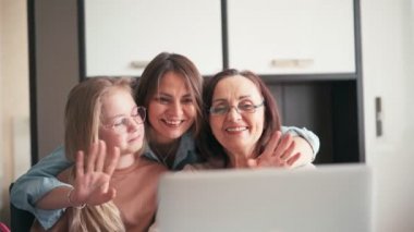 Büyükanne, anne ve torun el sallarken görüntülü arama yapıyorlar.