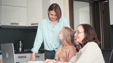A grandmother in eyeglasses and a mother helping daughter with her homework.