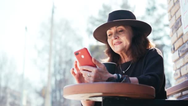 En vacker mogen kvinna sitter på den öppna terrassen i caféet — Stockvideo