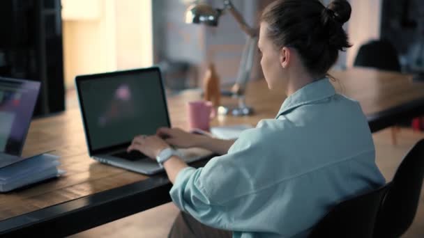 Parlak ofiste otururken dizüstü bilgisayarda yazan genç bir kadın.. — Stok video