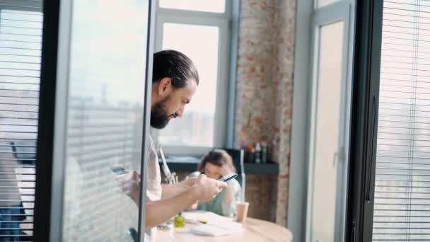 A handsome bearded man stands in the office doorway with a phone in his hands — Stock Video