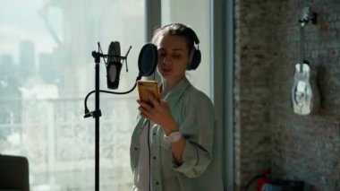 Spiker kayıt stüdyosundaki reklam metnini kaydeder..