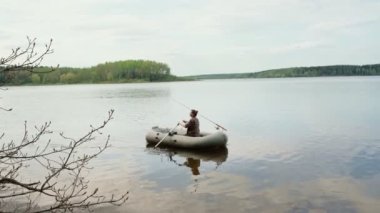 Genç kadın balıkçı gölde şişme bir teknede kürek çekiyor..