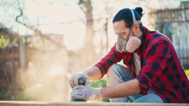 İnşaat solunum cihazındaki genç bir adam zımpara makinesiyle parke tahtasını öğütüyor.