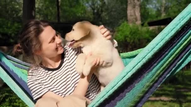 Mujer joven divirtiéndose jugando con su pequeño perrito labrador lindo — Vídeos de Stock