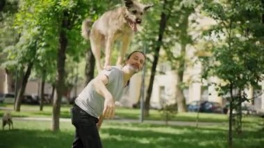 Yakışıklı sakallı bir adam akıllı köpeğini eğitiyor.