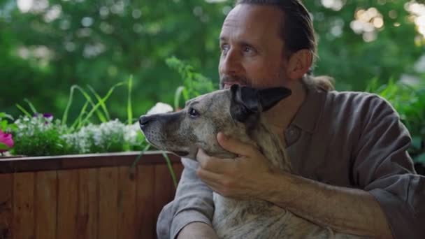Egy jóképű, szakállas, szelíd, középkorú férfi ölelgeti a kutyáját. — Stock videók