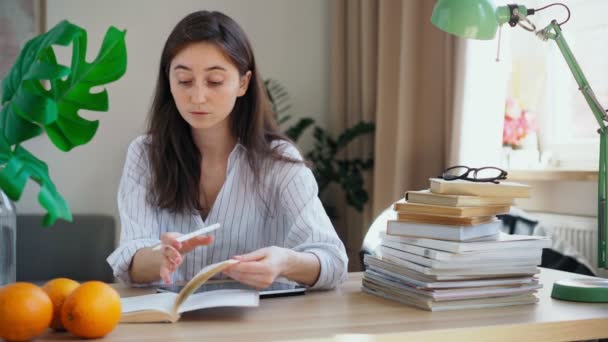 Ung student som förbereder sig för tentamen skriver om en föreläsning från en bok till en surfplatta — Stockvideo