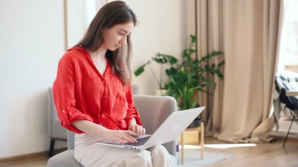Eine schöne junge Geschäftsfrau im knallroten Hemd tippt auf einem Laptop — Stockvideo