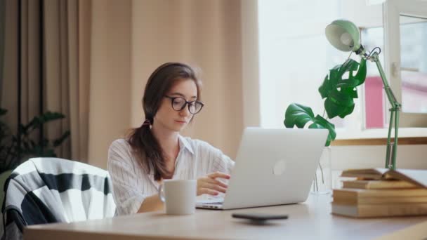 Ung vacker kvinna skriva på en bärbar dator när du arbetar hemifrån — Stockvideo