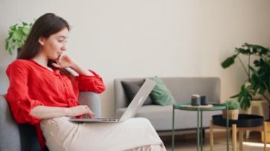 Parlak kırmızı gömlekli genç ve güzel bir iş kadını dizüstü bilgisayarında daktilo yazıyor.