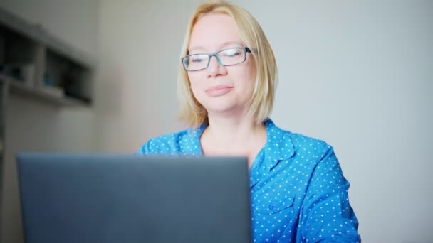 En kvinna som deltar i ett online-möte med kollegor på en bärbar dator hemifrån. — Stockvideo